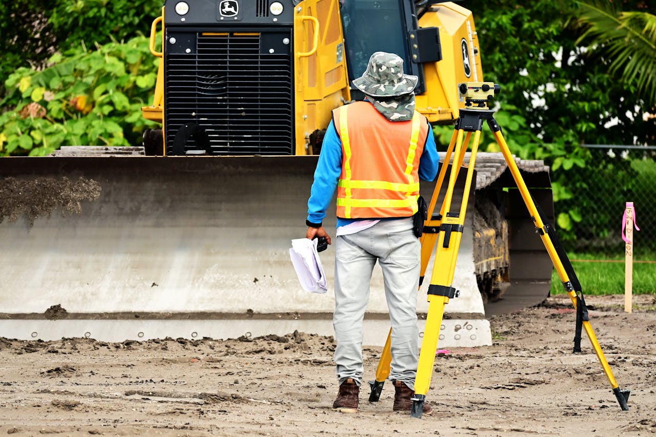 Crafting Captivating Headlines: Your awesome post title goes here Surveyor with equipment at an active construction site, observing bulldozer operations.