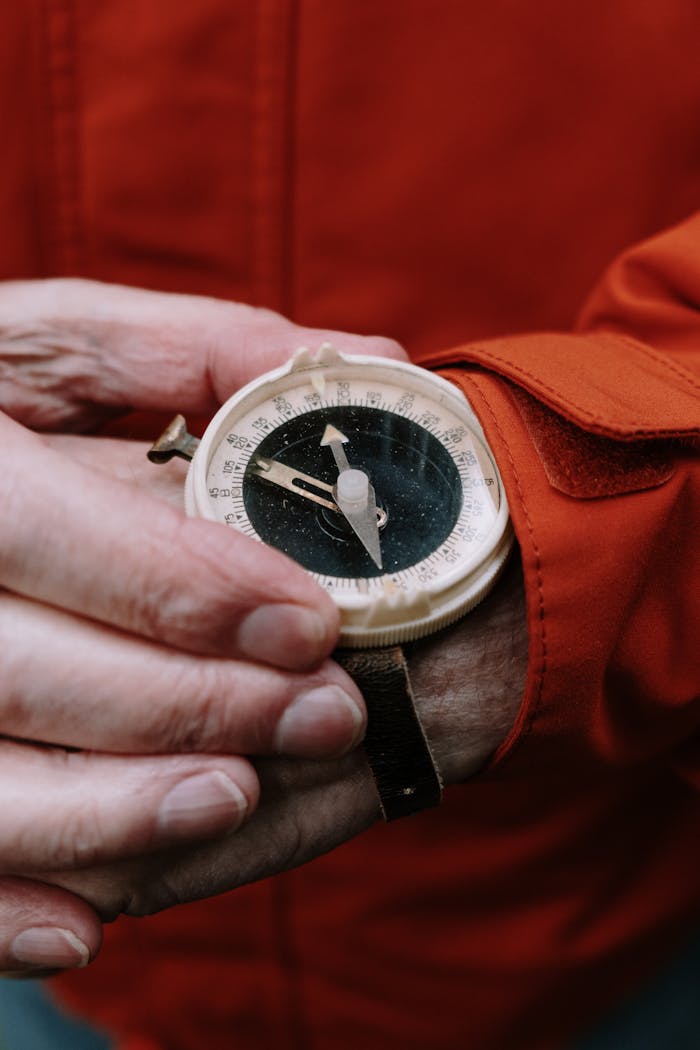 portfolio-02 Close-up of a vintage compass held by hands in an orange jacket, showcasing adventure and nostalgia.
