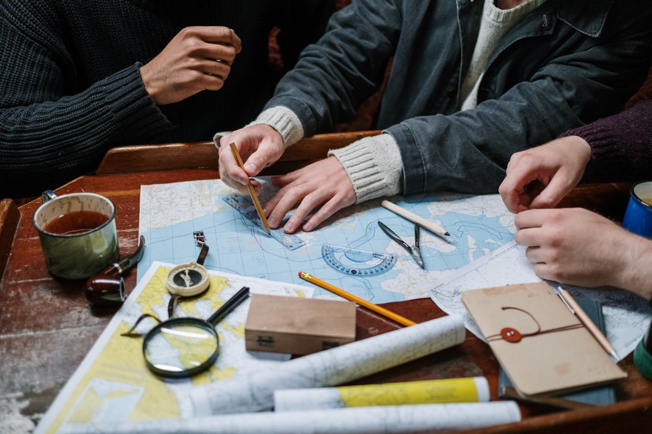 why-choose-us Adults planning a nautical journey using maps, compass, and tools indoors.